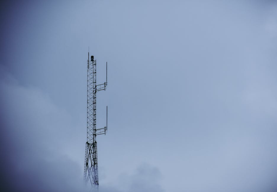 Telecommunication tower reaching into a cloudy sky, capturing modern technological infrastructure.